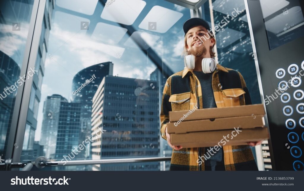 stockphotoyounghandsomespecialistridingglasselevatorinmodernofficebuildingrestaurantdelivery21368537991 iWorkZoom